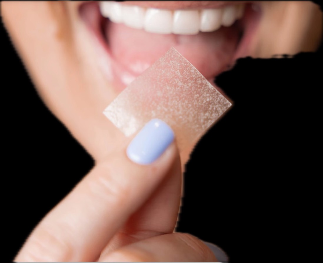 A person holding a thin, dissolving oral strip near their mouth